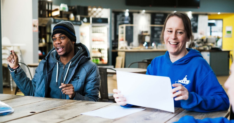Staff and a member sat at a table doing worksheets while smiling.